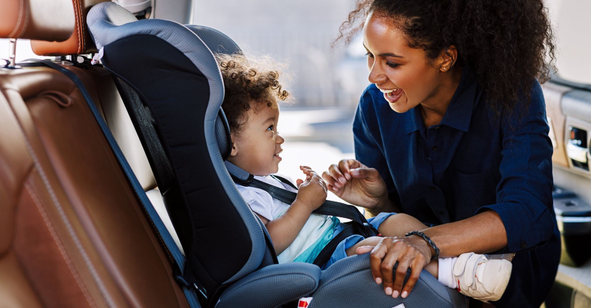 woman buckling her baby into a car seat 