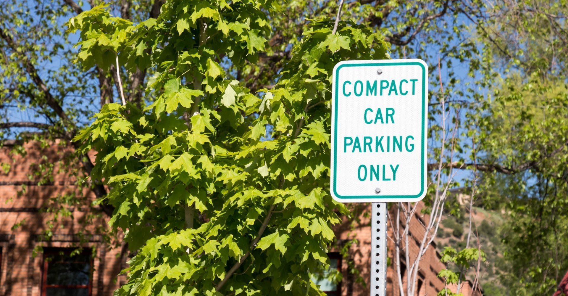 green and white street sign that reads" compact car parking only"