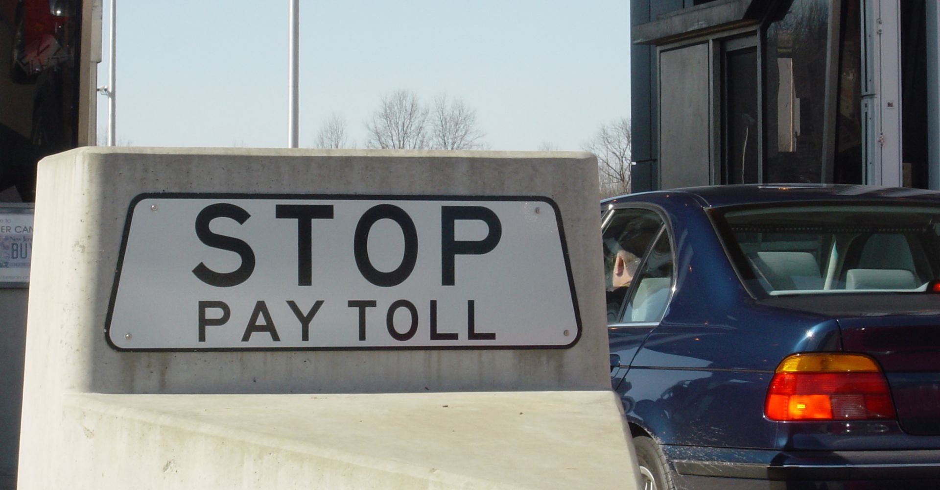 car pulled up alongside of a toll both reading "stop pay toll" 