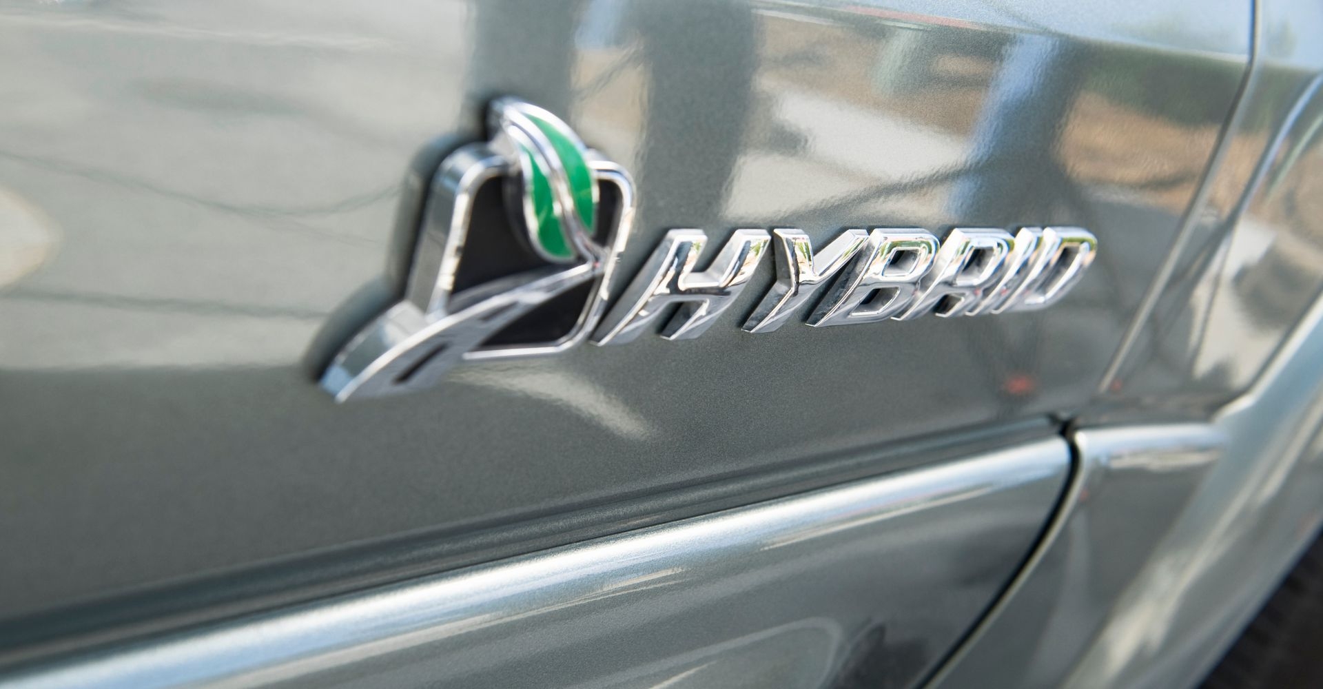 close up of a HYBRID decal on the side door panel of a silver car