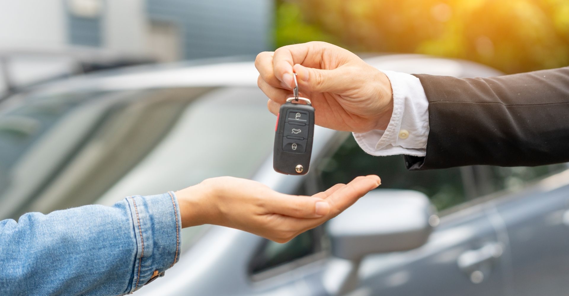 person handing a key fob over to the recipient of a car hire delivery 