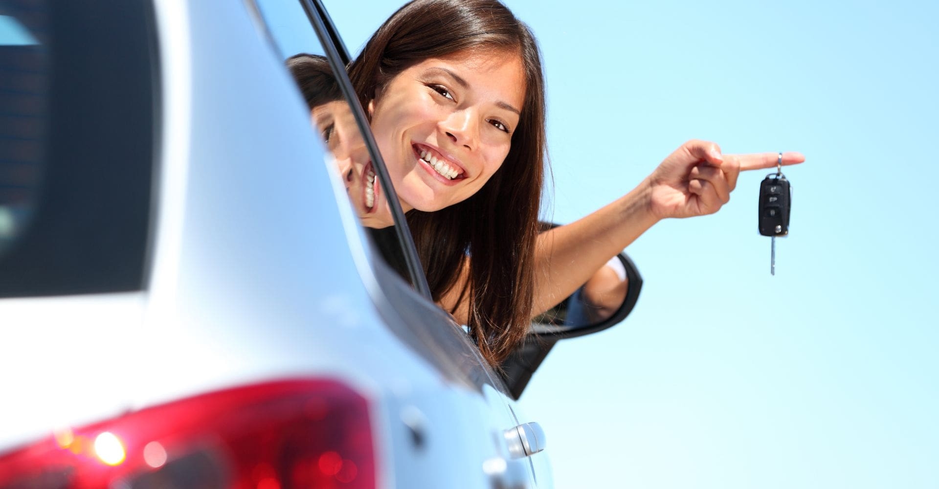 woman leaning out the window of a rental car holding the keys