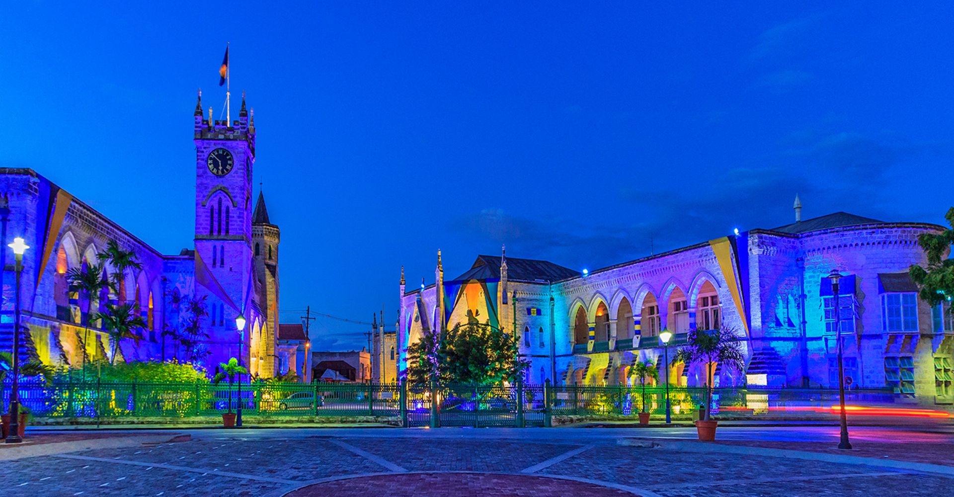 a street in Barbados at night illuminated with different colored shop lights 