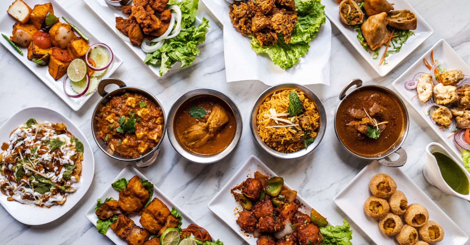 a sampler of Bajan food served on plates and in bowls shot from above on a white tablecloth 
