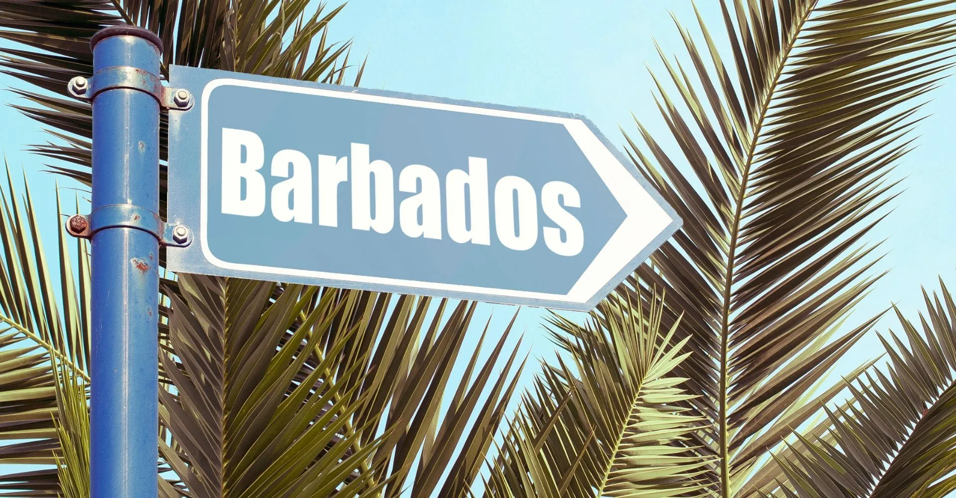 A street sign displaying the word "Barbados" against a clear blue sky