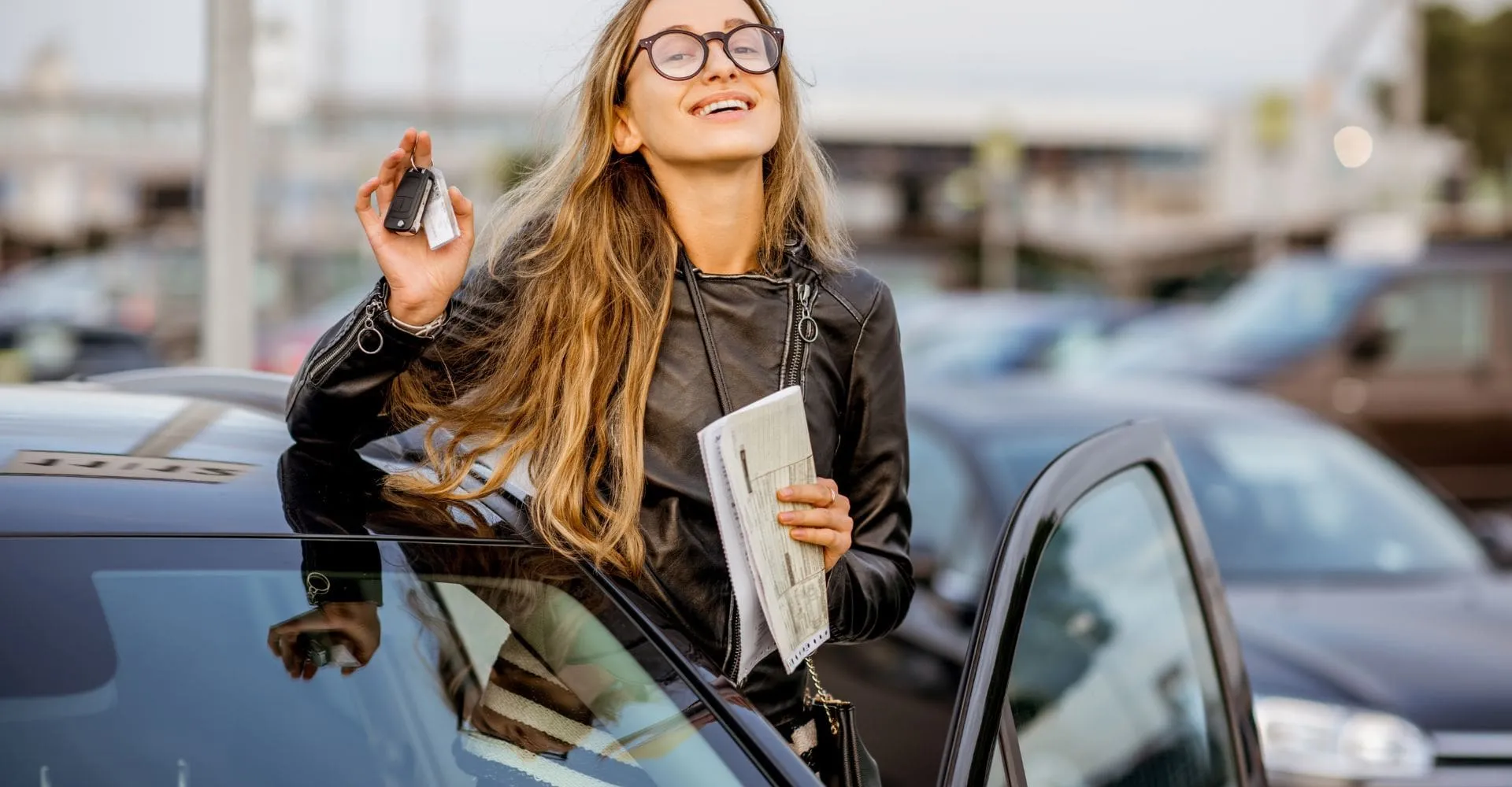 A woman smiles while holding a car key, expressing joy and excitement about her vehicle