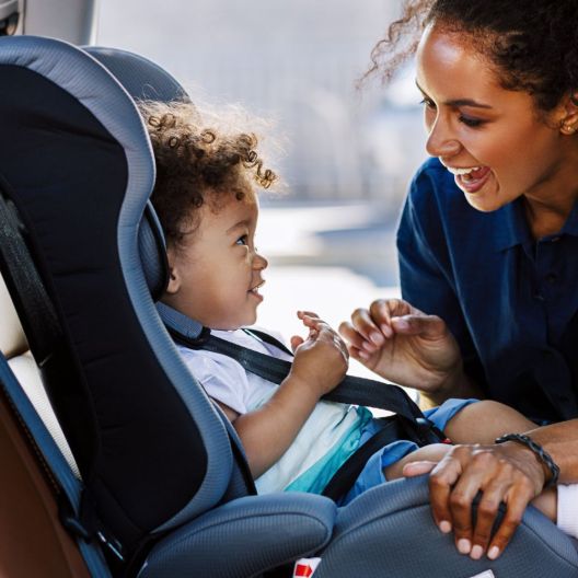 woman buckling her baby into a car seat 
