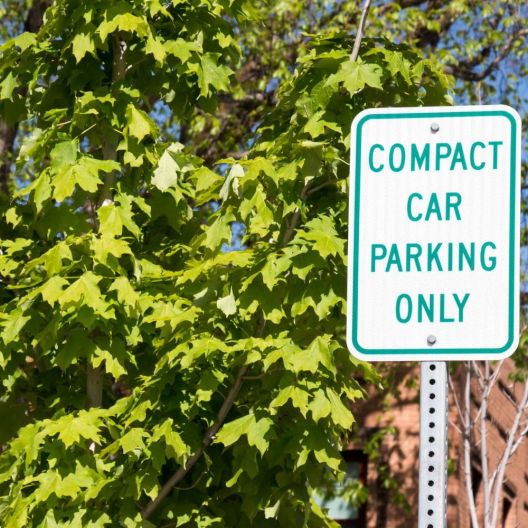 green and white street sign that reads" compact car parking only"
