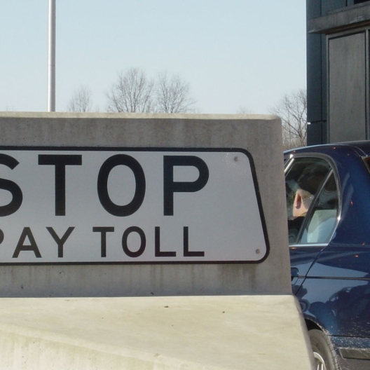 car pulled up alongside of a toll both reading "stop pay toll" 
