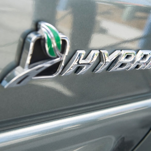 close up of a HYBRID decal on the side door panel of a silver car