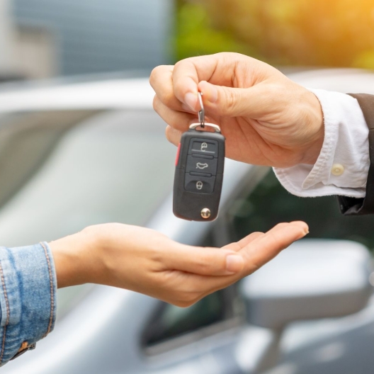 person handing a key fob over to the recipient of a car hire delivery 