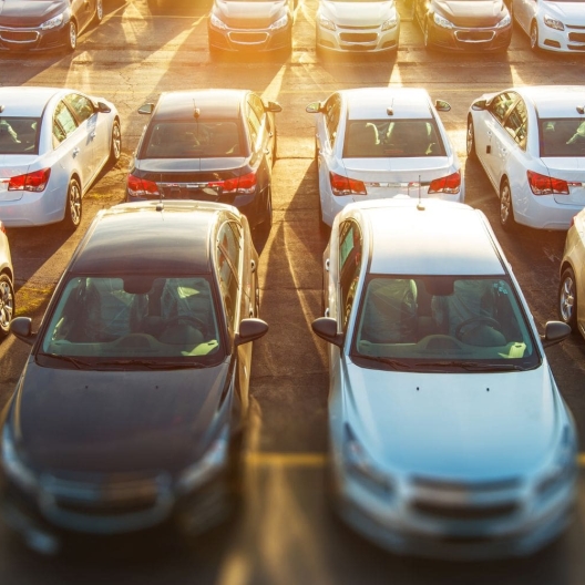 rows of rental cars parked in a parking lot 