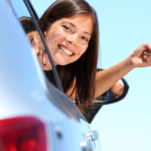 woman leaning out the window of a rental car holding the keys