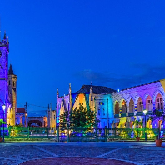 a street in Barbados at night illuminated with different colored shop lights 