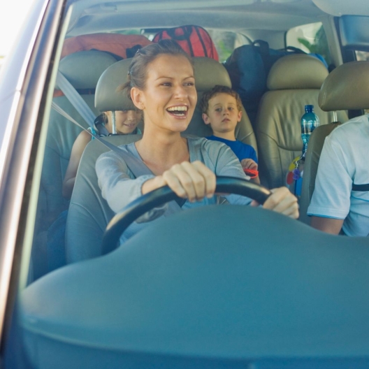 a family smiling in their rental car while driving down the road