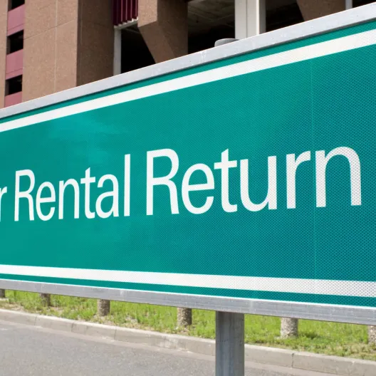green sign with white text that says "car rental return" 