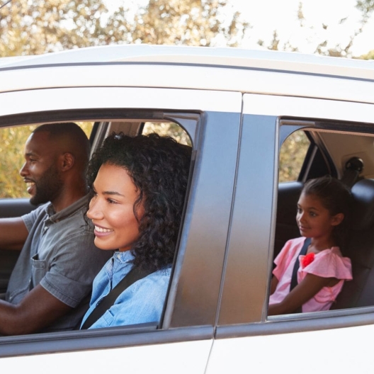 parents in front and kids in the back of a sedan looking excited about their trip 