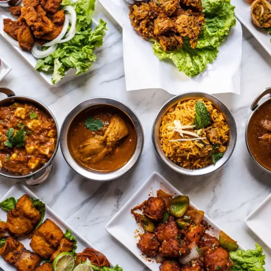 a sampler of Bajan food served on plates and in bowls shot from above on a white tablecloth 