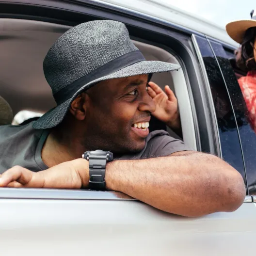 a couple and their child hanging out of the windows of their rental car getting ready to take a road trip 