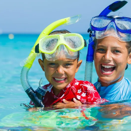 two boys with goggles and snorkels posing for a photo in the water 