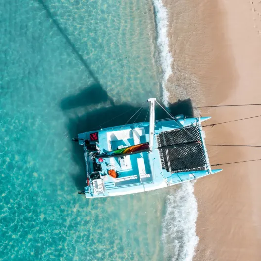 A small boat resting on the sandy beach, with gentle waves lapping at its sides under a clear blue sky
