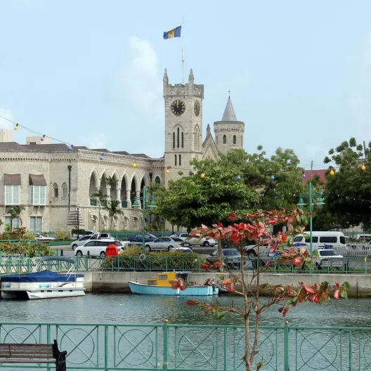  A city skyline featuring a prominent clock tower beside a flowing river under a clear blue sky